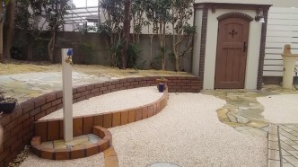 花壇に上がるステップを作り、 その横に白の木調の立水栓。